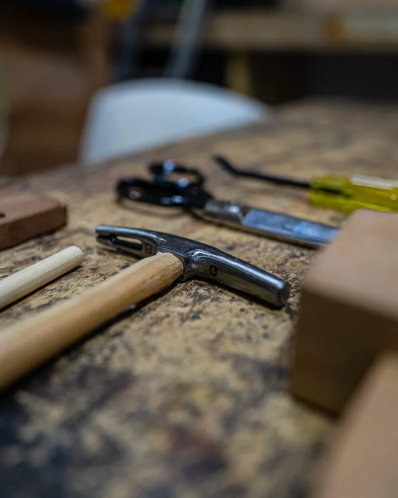 Set of upholstery tools, including a mallet and scissors on workshop bench