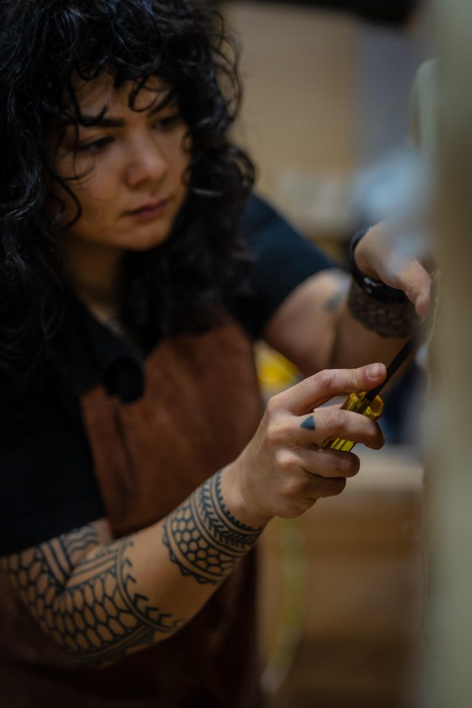 Rebecca Subido using a mallet and chisel on furniture