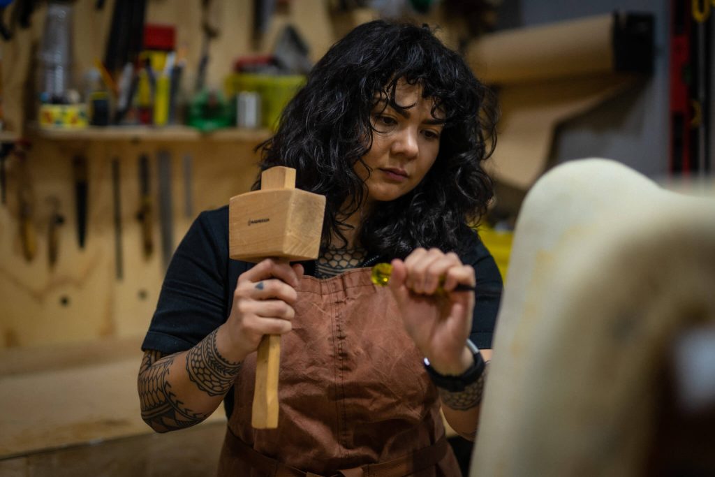 Rebecca Subido using a mallet and chisel on chair