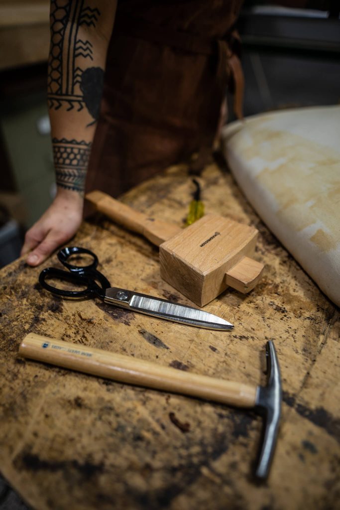 Set of upholstery tools, including a mallet and scissors on workshop bench