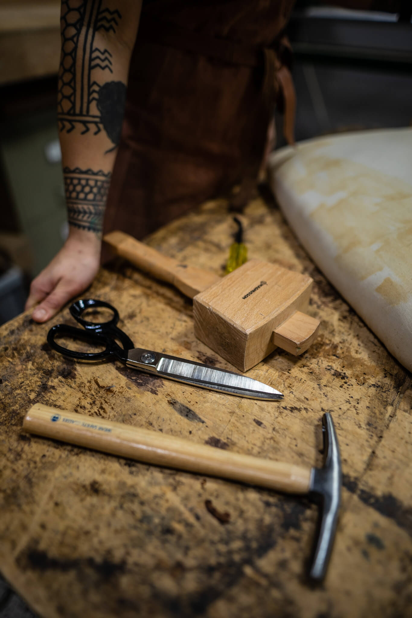 Set of upholstery tools, including a mallet and scissors on workshop bench