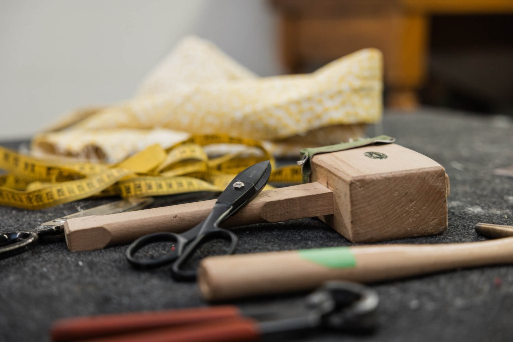 Set of upholstery tools, including a mallet, scissors and fabric on workshop bench